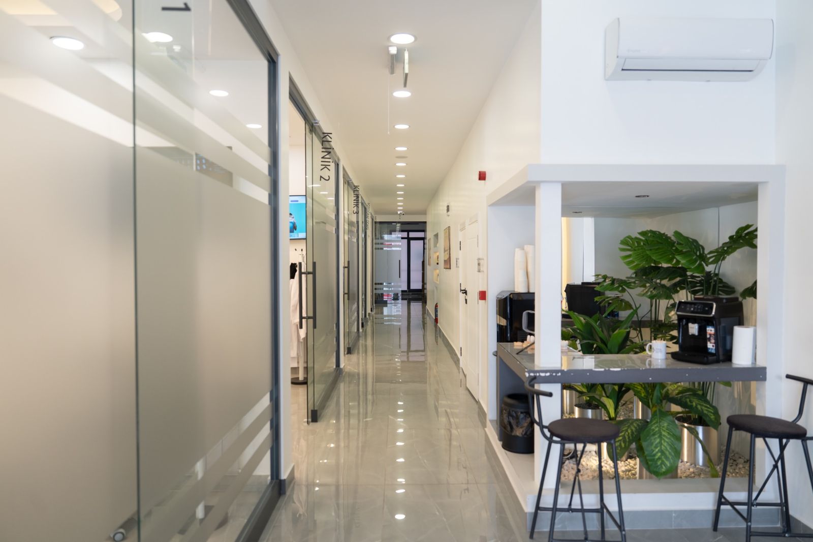 The main corridor at TORA Clinic, with glass-walled rooms along one side.