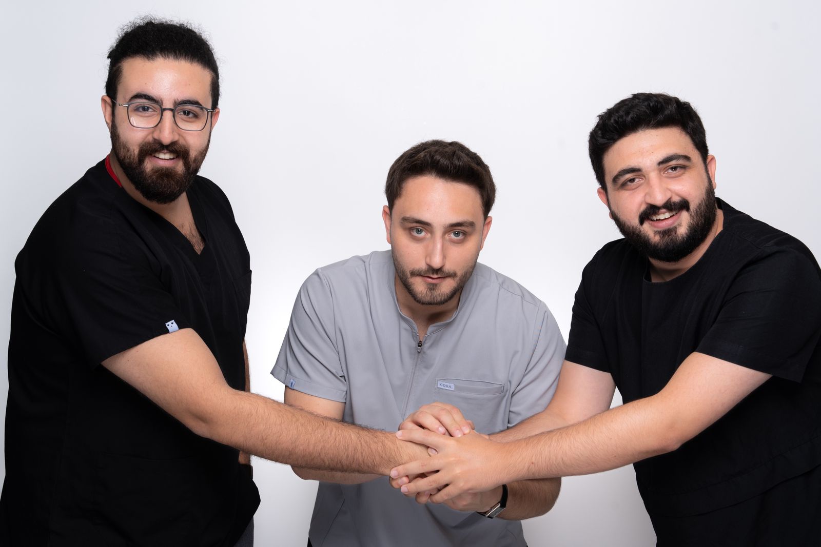 The three founding doctors of TORA Clinic joining their hands together.